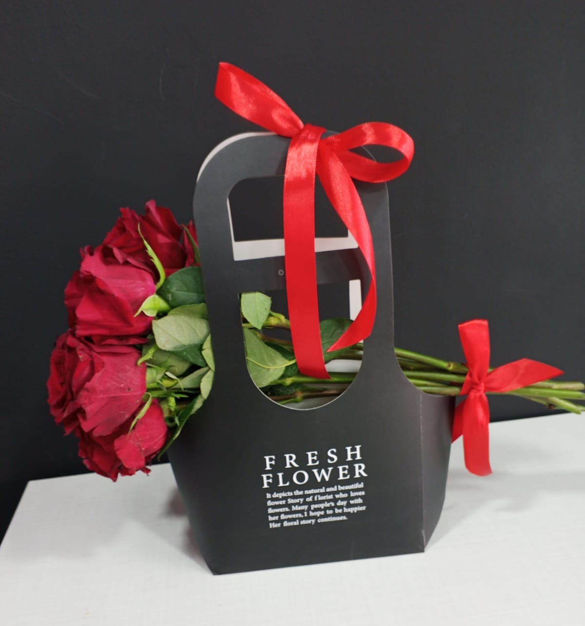 Red roses in black gift carrier box with red satin ribbon